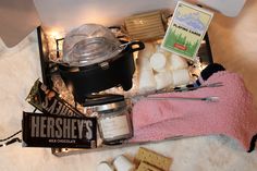 an assortment of food is displayed on a white tablecloth with a pink towel and some marshmallows