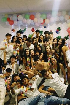 a group of young people posing for a photo in front of balloons and garlands