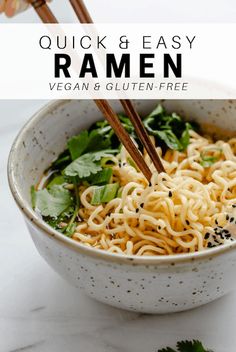 a white bowl filled with noodles and greens next to chopsticks in the bowl