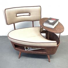 a chair with a book on top of it next to a small table and a magazine rack