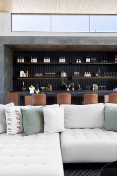 a living room filled with furniture and lots of shelves full of bottles on the wall