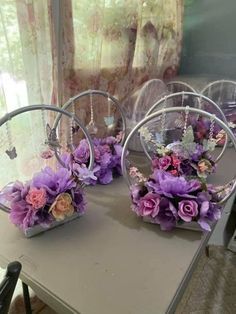 purple flowers are placed in baskets on a table