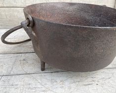 an old cast iron pot sitting on top of a white wooden floor next to a wall