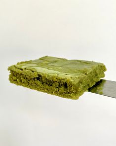 a piece of green cake being held by a knife