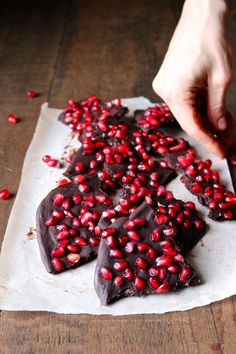 someone is placing pomegranates on top of the chocolate hearts that they made