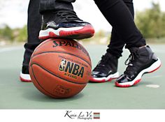 a person standing on top of a basketball next to another persons foot wearing black and red sneakers