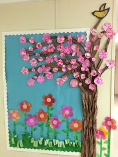 a paper tree with pink flowers and a yellow bird on it, next to a blue wall