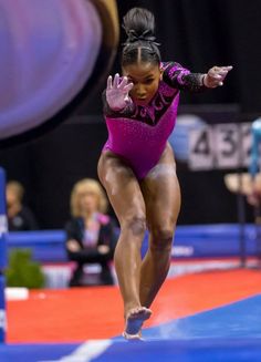 a woman in a purple leotard doing gymnastics