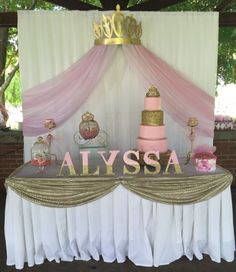 a pink and gold cake sitting on top of a table