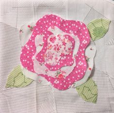 a close up of a pink flower on a piece of fabric with green leaves and polka dots