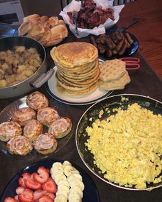 a table topped with lots of different types of breakfast foods next to plates of food