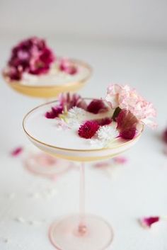 pink and white flowers are placed on two small plates with gold rims, sitting on a table