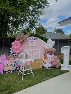 an outdoor party with balloons and farm animals on the lawn, including a pink barn