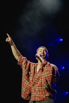 a male in a plaid shirt is singing into a microphone