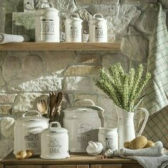 kitchen utensils are displayed on an old wooden table in front of a stone wall