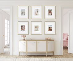 a white room with framed pictures on the wall and a table in front of it