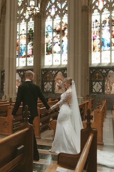 the bride and groom are walking down the aisle at their wedding in front of stained glass windows