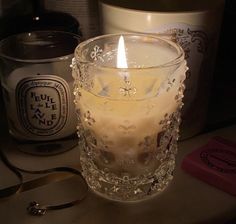 a lit candle sitting on top of a table next to some jars and spoons