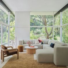 a living room filled with lots of furniture and large windows overlooking the trees in the background