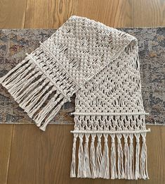 two pieces of woven fabric on a wooden floor next to a rug with fringes