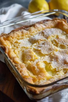 a casserole dish with lemons and powdered sugar in the background on a wooden table