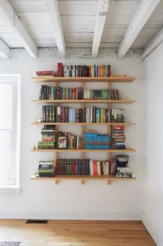 a bookshelf filled with lots of books on top of a hard wood floor