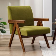 a green chair sitting on top of a hard wood floor next to a table and potted plant