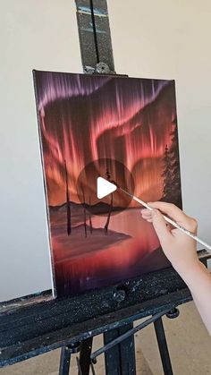 someone is painting an aurora bore in the night sky with their thumbnails and holding a paintbrush