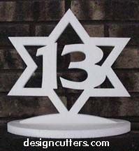 a white cake topper with the number thirteen in it's center on a stand next to a brick wall