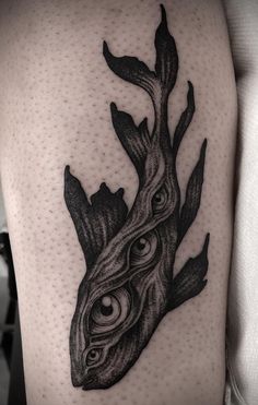 a black and white photo of a tattoo on the thigh