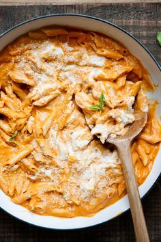 a bowl filled with pasta and sauce on top of a wooden table