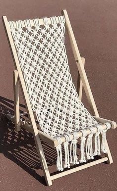 a white lawn chair with tassels sitting on top of a brown floor next to a wall