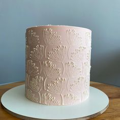 a pink and white cake sitting on top of a wooden table