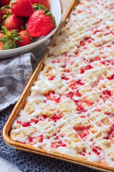 a close up of a tray of food with strawberries on the side and a bowl of strawberries in the background