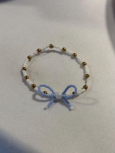 a blue and white beaded bracelet with a bow on the end is sitting on a table