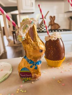 an easter bunny next to a chocolate egg on a table with confetti sprinkles