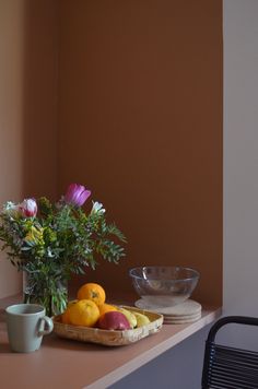 a bowl of fruit and flowers on a table