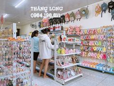 two women are looking at items in a store that is filled with dolls and souvenirs