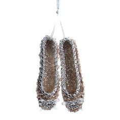 two pairs of shoes hanging from a string on a white background with silver beads and chains