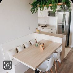 a kitchen table with four chairs and a plant hanging from the ceiling in front of it