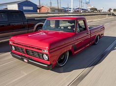 an old red truck driving down the road