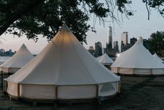 several tents are set up near the water in front of a large cityscape