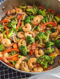 shrimp and broccoli stir - fry in a skillet on a blue towel