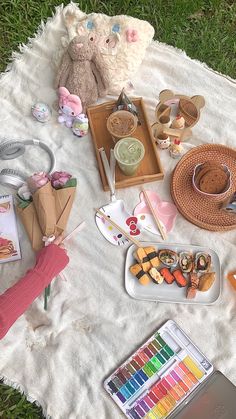 a picnic blanket on the grass with some food and other items laid out next to it