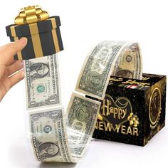 a hand holding a black and gold gift wrapped in money