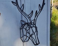 a metal deer head mounted to the side of a white door in front of a grassy field