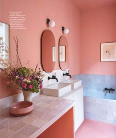 a bathroom with pink walls and white counter tops, two sinks and mirrors on the wall