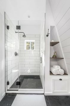 a walk in shower sitting next to a white bathroom sink and toilet paper on the shelf