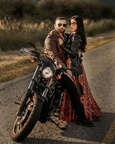 a man and woman sitting on a motorcycle in the middle of the road with their arms around each other