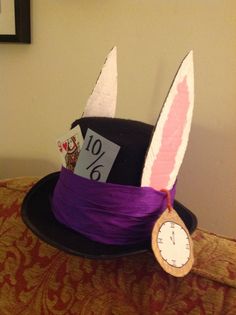 a purple hat with bunny ears and tags on it is sitting on a table next to a clock